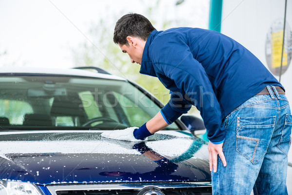 Hard-working man polishing car with white microfiber mitt Stock photo © Kzenon