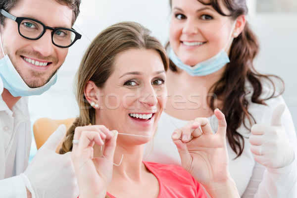 Woman at dentist using dental floss Stock photo © Kzenon