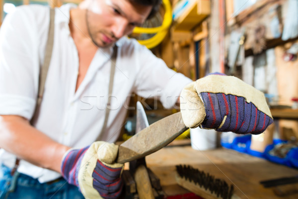 Young man sharpening tools in mountains hut Stock photo © Kzenon