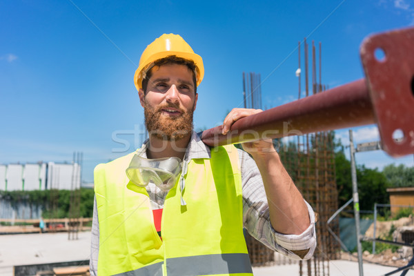 Blue-collar worker carrying a heavy metallic bar during work on  Stock photo © Kzenon