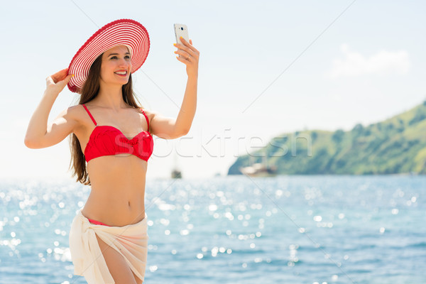 Beautiful young woman wearing a trendy striped hat at the beach Stock photo © Kzenon
