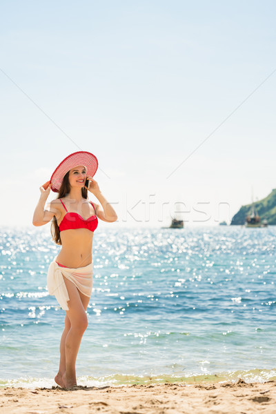 Fashionable fit young woman talking on mobile phone on the beach Stock photo © Kzenon