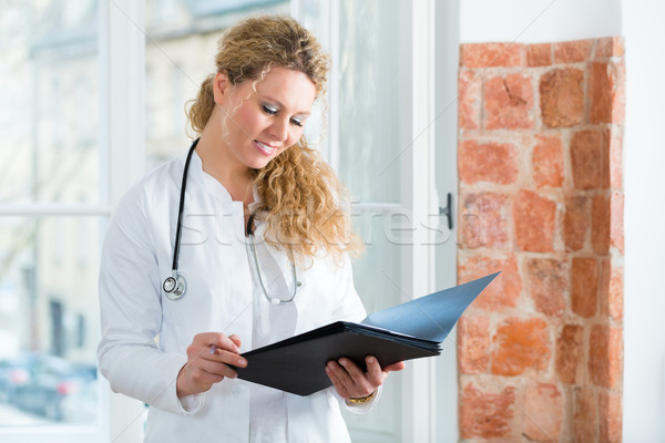Doctor in clinic reading a file Stock photo © Kzenon