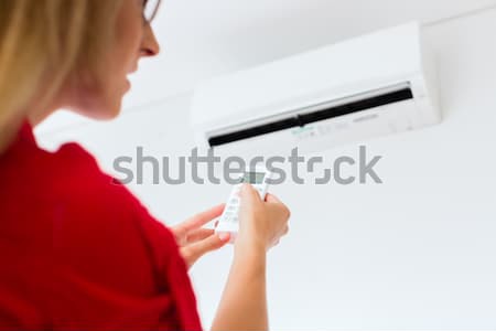 Woman using air-condition with remote control Stock photo © Kzenon