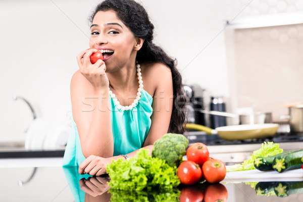 Indian woman eating healthy apple in her kitchen Stock photo © Kzenon