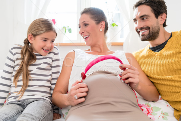 Family and pregnant mum using headphone on baby belly Stock photo © Kzenon