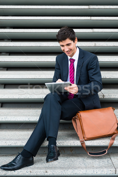 Businessman using a tablet for communication or data storage out Stock photo © Kzenon