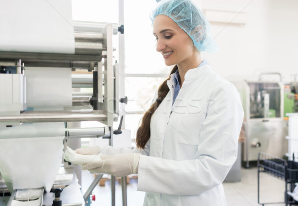 Happy employee wearing lab coat while handling sterile wipes Stock photo © Kzenon