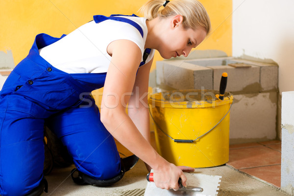 Female tiler tiling tiles on the floor Stock photo © Kzenon