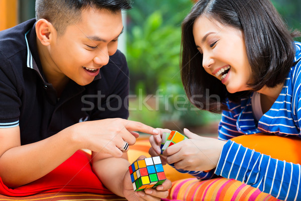 Asian couple at home playing with magic cube Stock photo © Kzenon