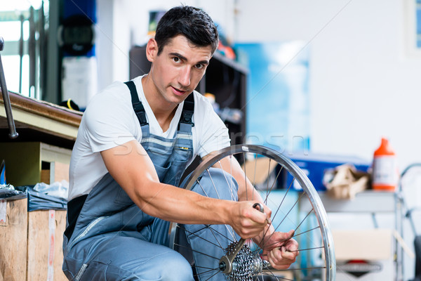 Man as bicycle mechanic working in workshop Stock photo © Kzenon