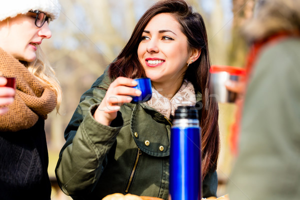 Young female friends drinking a hot beverage outdoors in winter Stock photo © Kzenon