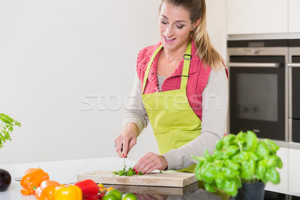 Woman in kitchen cutting herbs Stock photo © Kzenon