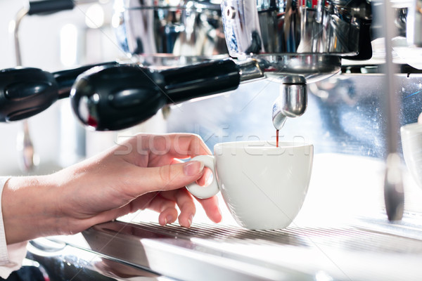 Stock photo: Close-up of female hand on the portafilter of an automatic coffe
