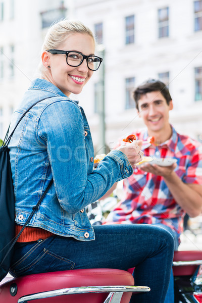 Stock photo: Tourist couple taking rest during scooter tour eating currywurst