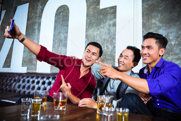 Asian friends taking pictures or selfies in fancy night club Stock photo © Kzenon