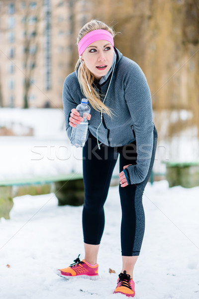 Stock photo: Woman listening to music while having break from running sport i