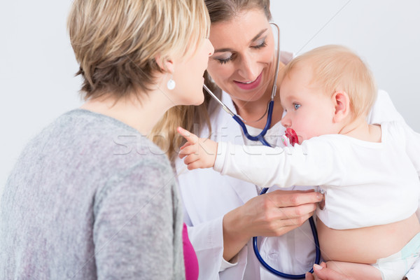 Dedicated female physician holding a cute baby girl in her arms  Stock photo © Kzenon