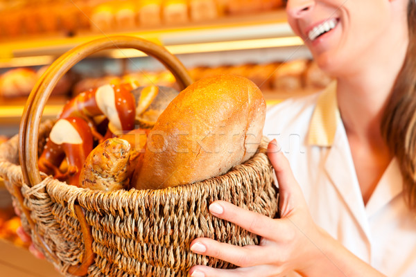 Female baker selling bread by basket in bakery Stock photo © Kzenon