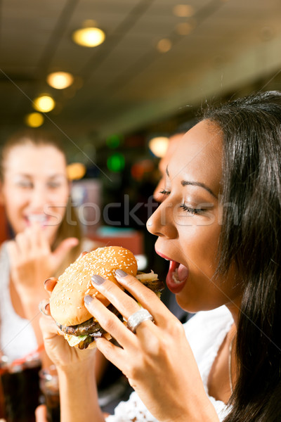 Friends eating fast food in a restaurant Stock photo © Kzenon
