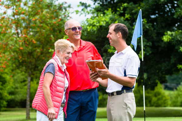 Golf pro with senior woman and man analyzing results Stock photo © Kzenon