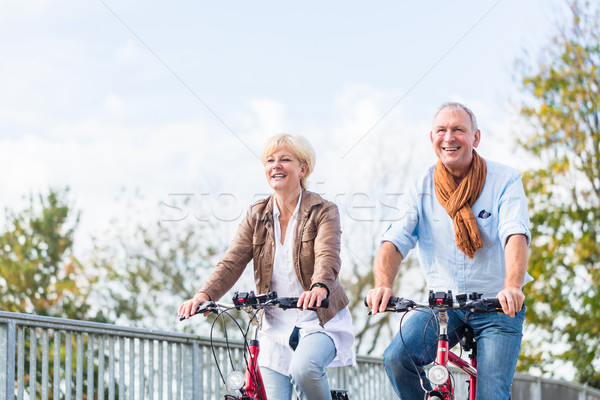 Senior couple with bicycles on bridge Stock photo © Kzenon