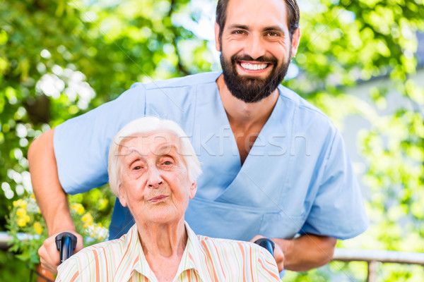 Geriatric nurse pushing senior lady in wheel chair thru home Stock photo © Kzenon