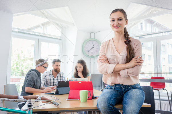 Portrait of a successful entrepreneur sitting on a desk in the office Stock photo © Kzenon