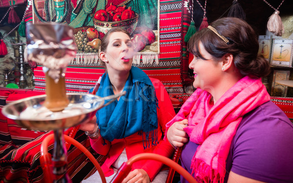 Women enjoying hookah or shisha in oriental cafe Stock photo © Kzenon