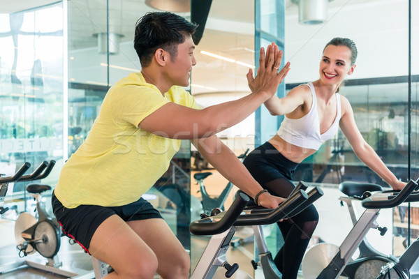 Cheerful young man and his workout partner giving high five during workout Stock photo © Kzenon