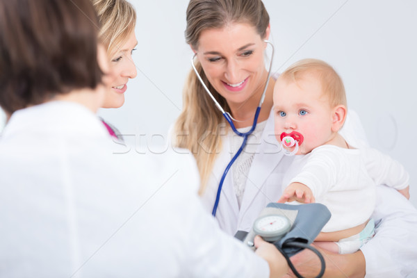 Dedicated female physician holding a cute baby girl in her arms  Stock photo © Kzenon