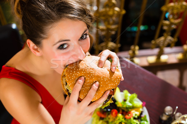 Young woman in fine restaurant, she eats a burger Stock photo © Kzenon