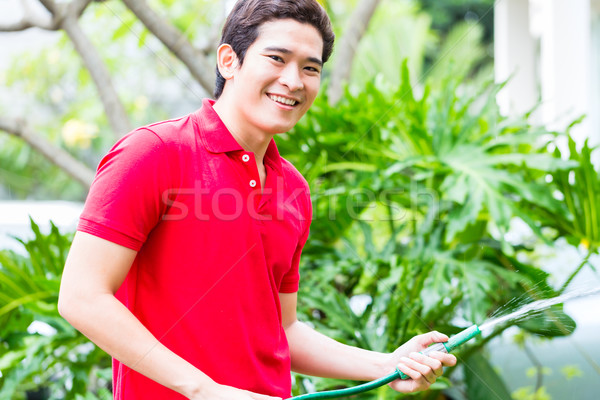 Asian man watering plants with garden hose   Stock photo © Kzenon