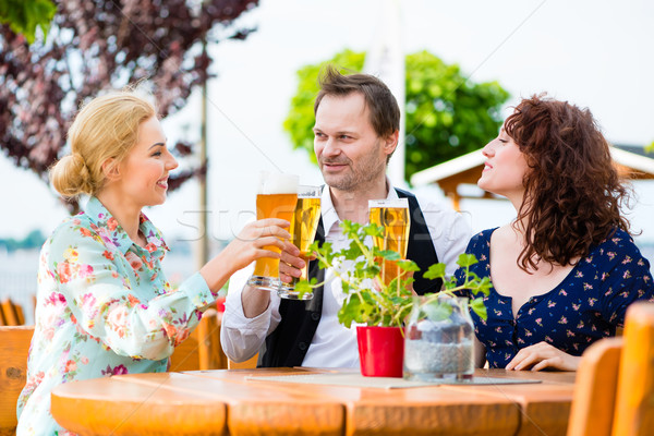 Friends toasting with beer in garden restaurant Stock photo © Kzenon