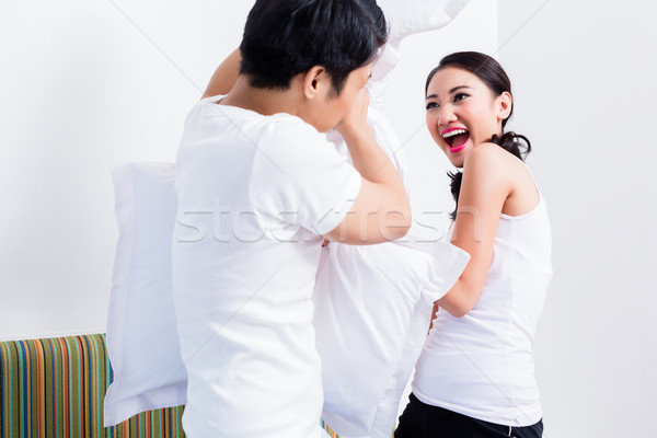 Chinese Woman and man having pillow fight Stock photo © Kzenon