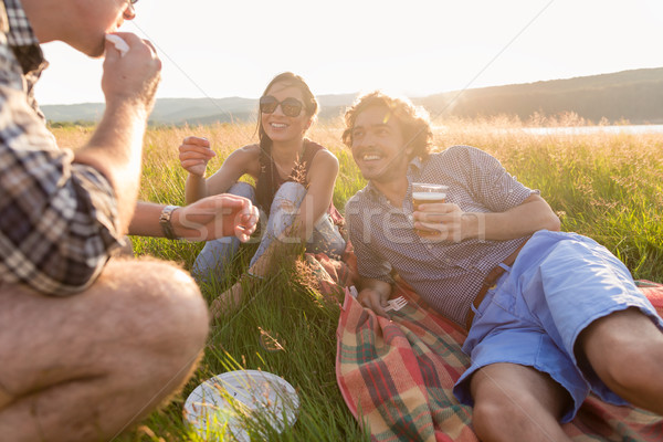 Friends sitting in grass and having burgers at barbecue party  Stock photo © Kzenon