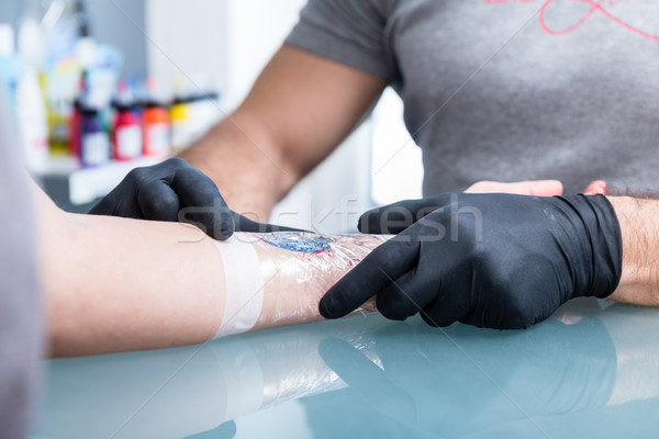 Close-up of the hand of a tattoo artist shading a colorful butterfly Stock photo © Kzenon