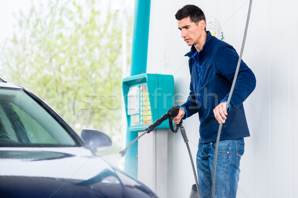 Dedicated worker washing car with high-pressure hose Stock photo © Kzenon