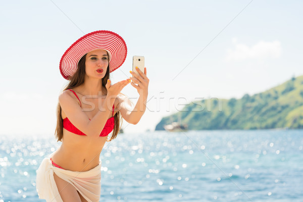 Beautiful woman blowing a kiss while sharing on social media a s Stock photo © Kzenon
