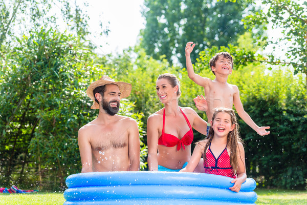 Family cooling down splashing water in garden pool  Stock photo © Kzenon