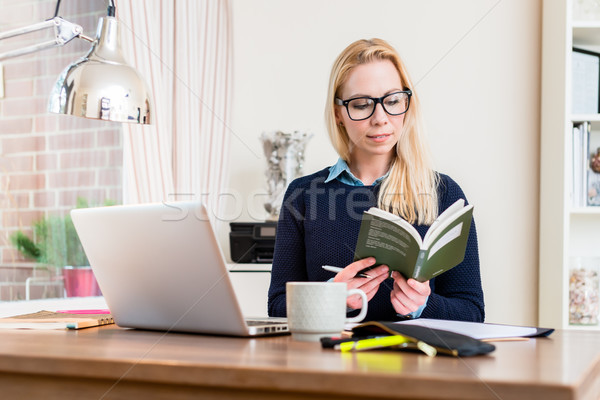 Woman at her desk reading book Stock photo © Kzenon