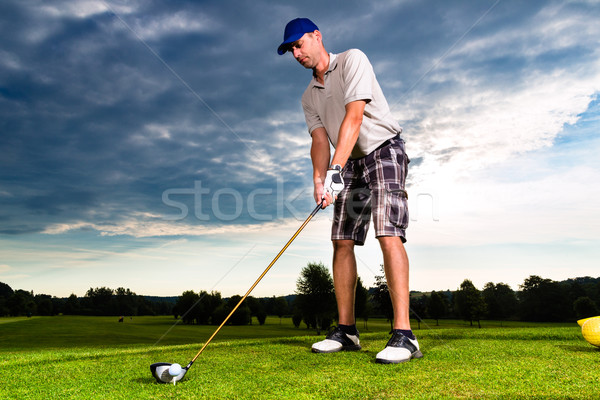 Young golf player on course doing golf swing Stock photo © Kzenon