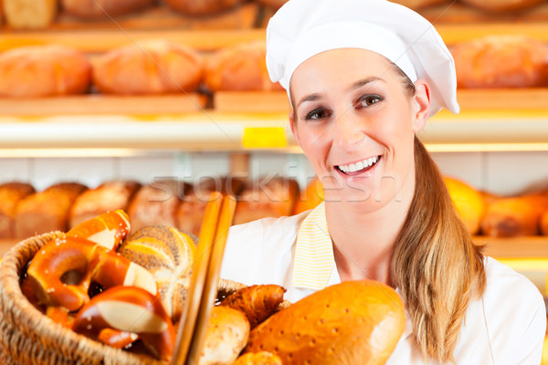 Female baker selling bread by basket in bakery Stock photo © Kzenon