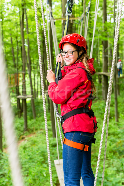 Girl roping up in high rope course Stock photo © Kzenon