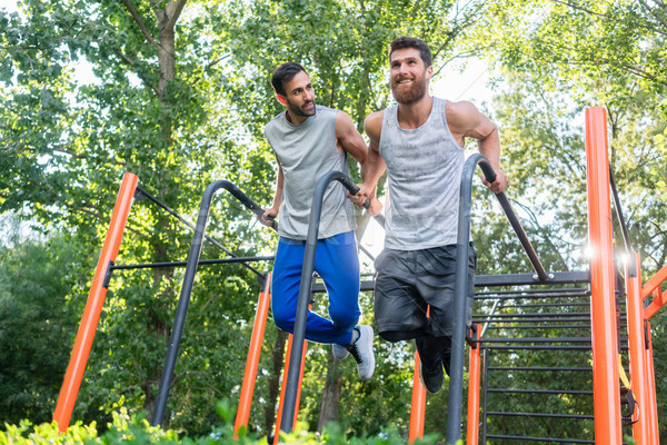 Two handsome young men passionate about fitness doing dips exerc Stock photo © Kzenon