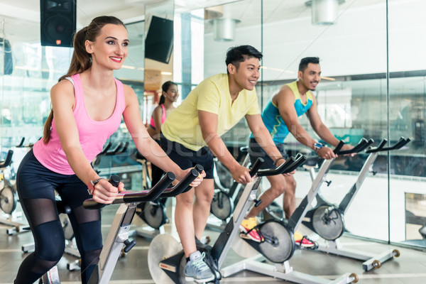 Fit women burning calories during indoor cycling class Stock photo © Kzenon