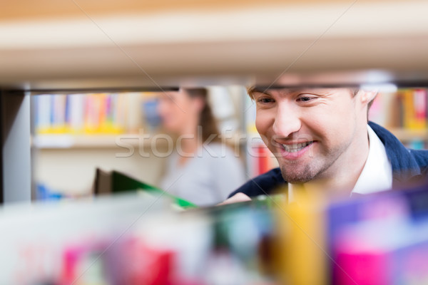 Man looking through shelf of books choosing volume to read Stock photo © Kzenon