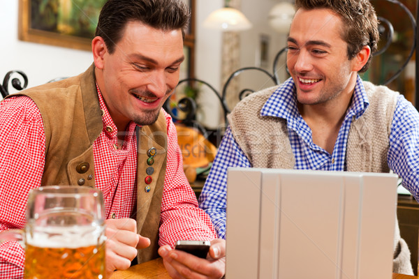 Two friends in Bavarian pub with laptop Stock photo © Kzenon