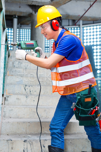 Asian worker drilling in construction site wall Stock photo © Kzenon