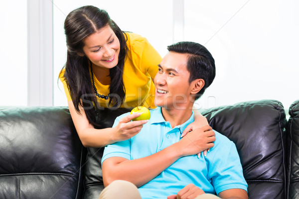 Stock photo: Asian woman feeding boyfriend on sofa or couch